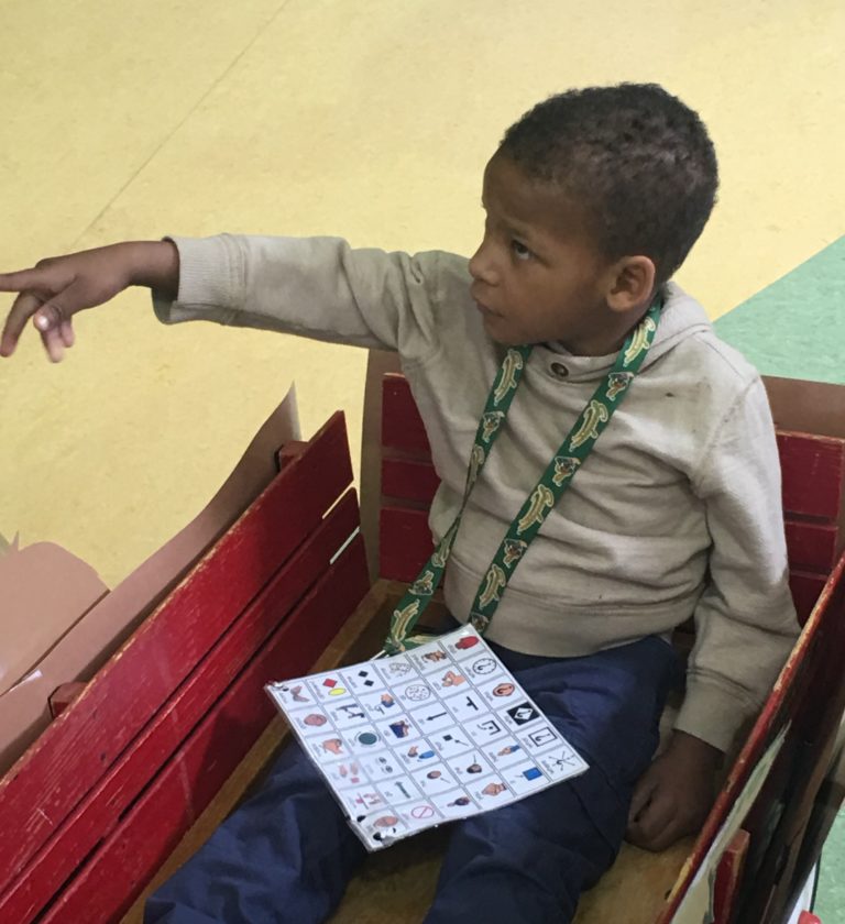 young boy in a wagon pointing