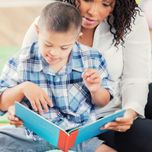 teacher reads a book with a student